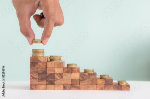 Wooden block stacking as staircase level with golden coins on top, business growth concept