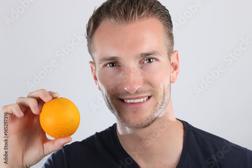 Jeune homme tenant une orange sur un fond blanc  © rdrgraphe