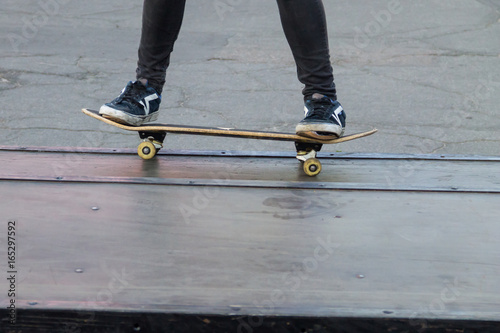 Skateboarder legs riding skateboard at skatepark © olyasolodenko