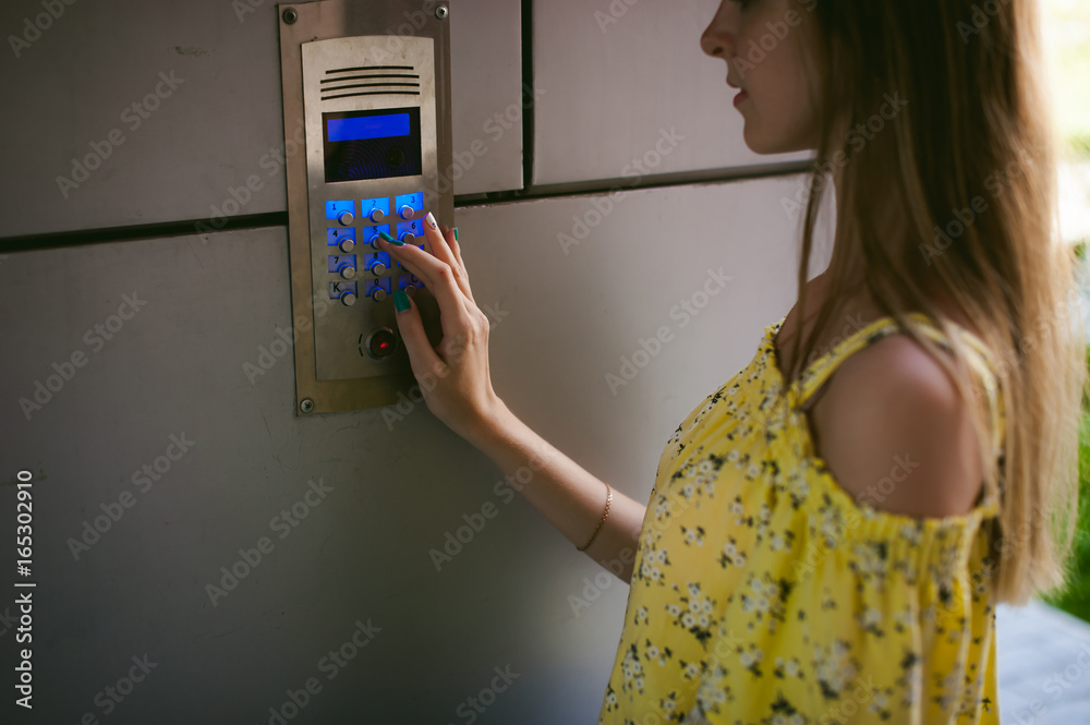 woman dials an apartment code on an electronic doorphone panel woman dials an apartment code on an electronic doorphone panel