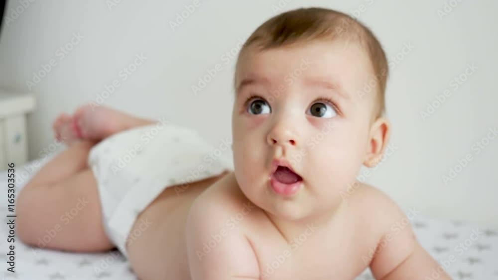 baby boy in diaper lying on her belly on the diaper with the stars next to a white wall on the table of the house baby boy in diaper lying on her belly on the diaper with the stars next to a white wall on the table of the house