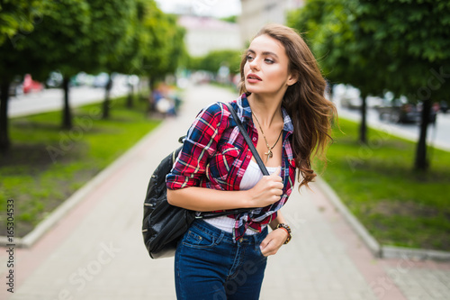 Young female student with backpack walking in the park