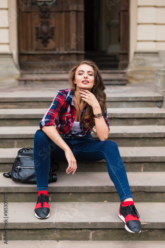 Portrait of a beautiful young woman sitting on stairs outdoors beautiful young woman smiling © F8  \ Suport Ukraine