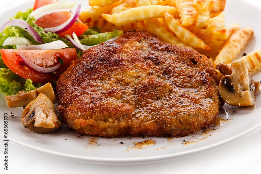 Fried pork chop, French fries and vegetable salad on white background