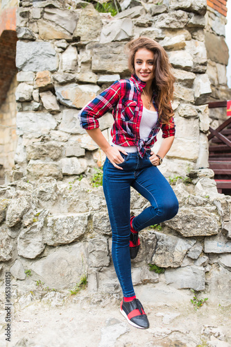 Pretty young slim woman posing against stone wall