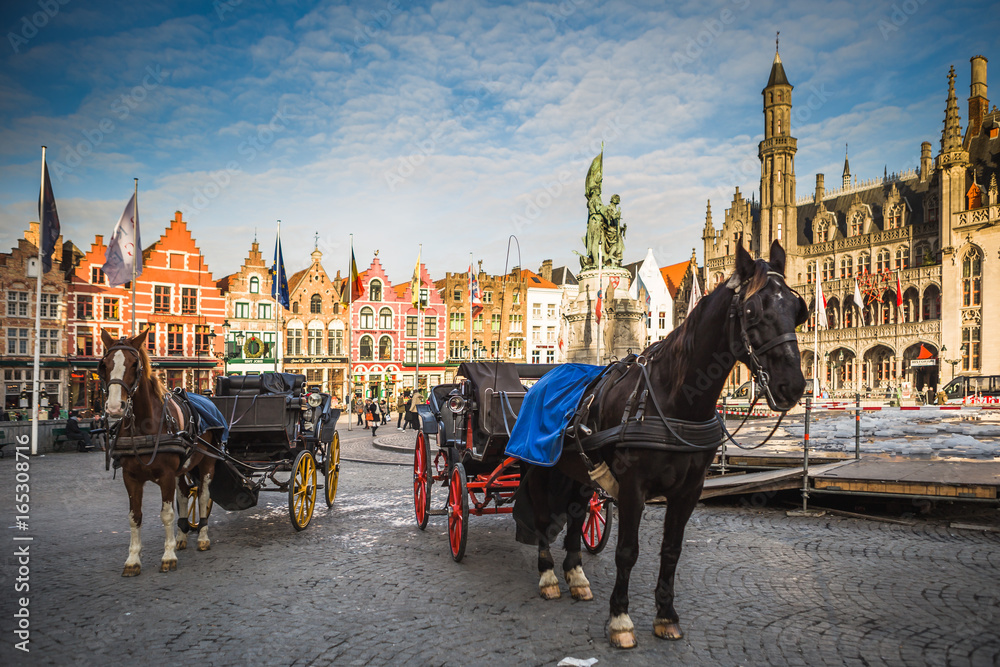 Naklejka premium Bryczki konne na placu Grote Markt w średniowiecznym mieście Brugge rano, Belgia.