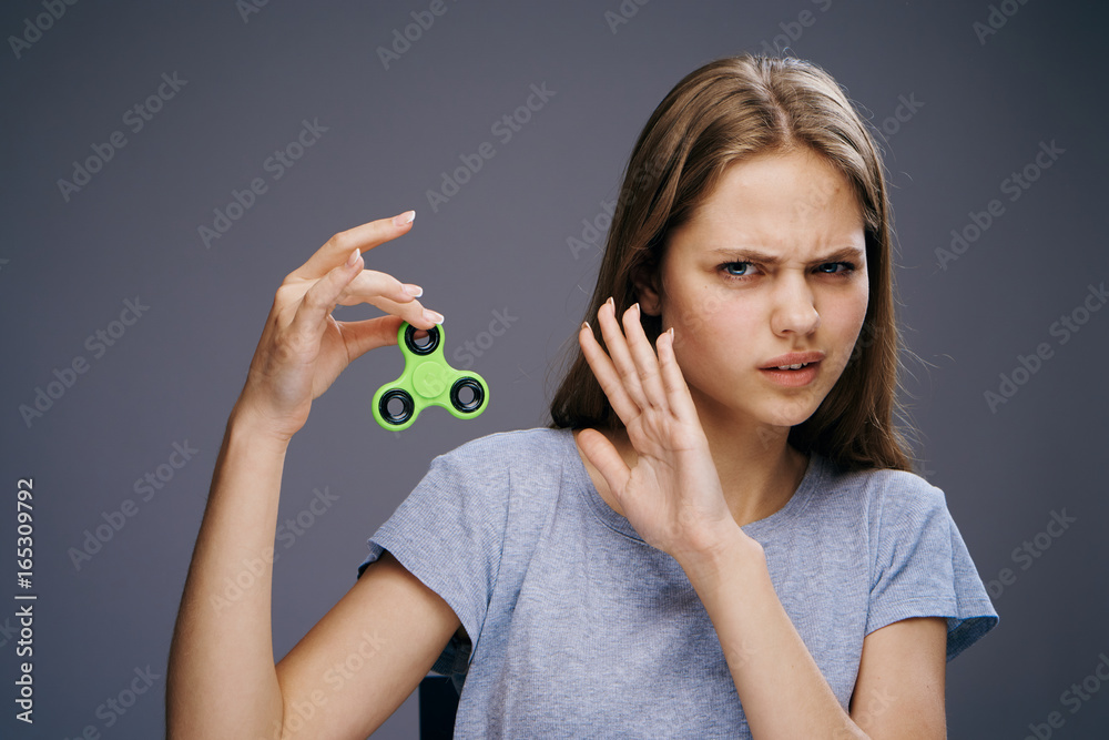 Beautiful young woman on a gray background holds a spinner Beautiful young woman on a gray background holds a spinner