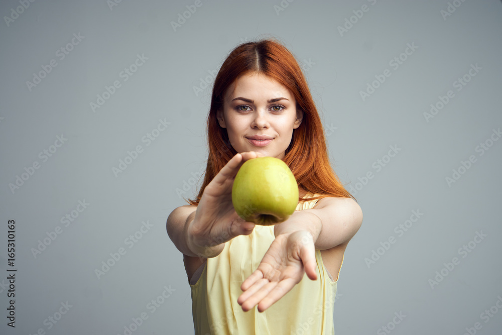 Beautiful young woman on a gray background holding an apple Beautiful young woman on a gray background holding an apple