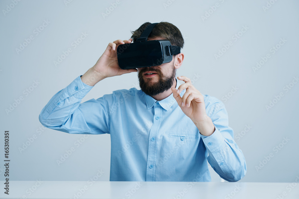 A young guy with a beard on a blue background with virtual reality glasses A young guy with a beard on a blue background with virtual reality glasses