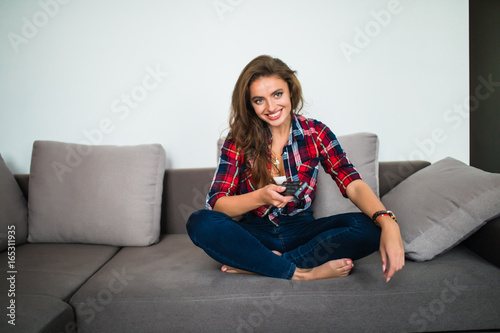 Young woman watching tv in the room sitting on sofa