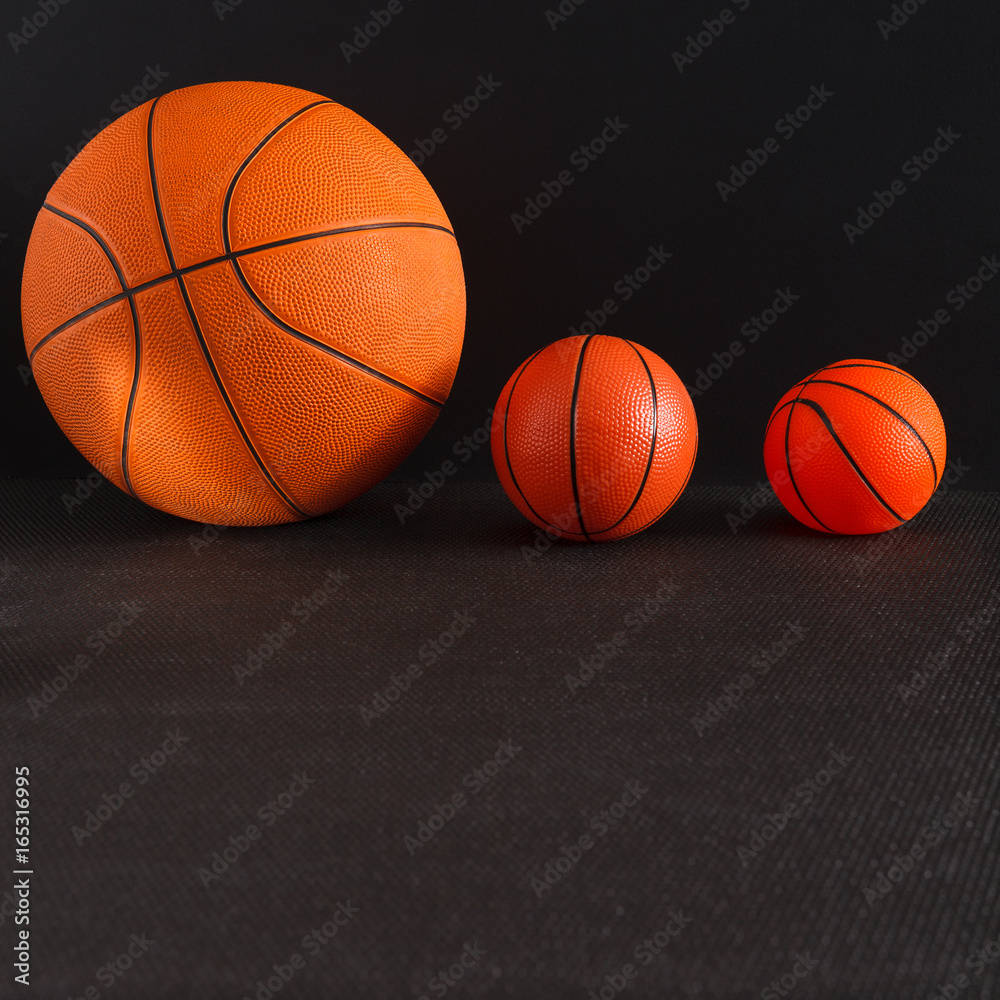 Big and small basketball balls on black background