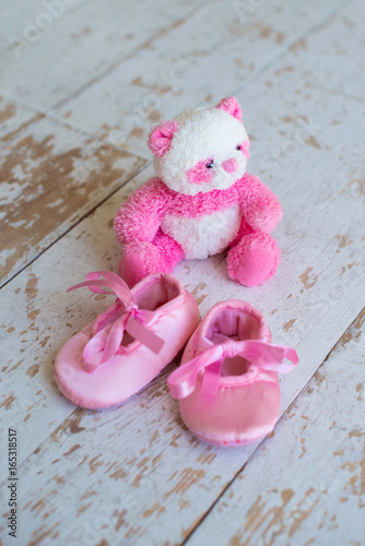 Little toy-teddy bear and children's shoes on a wooden background