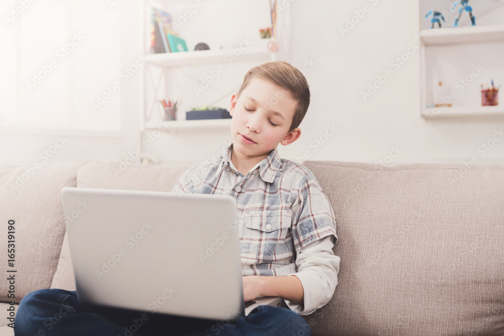 Teenage boy surfing the web on laptop on couch at home Teenage boy surfing the web on laptop on couch at home