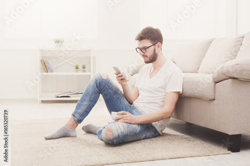 Serious young man at home with mobile