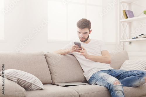 Young man at home messaging on mobile