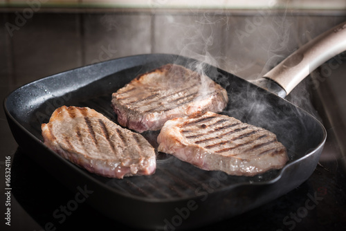cooking rib eye steak on grill pan.