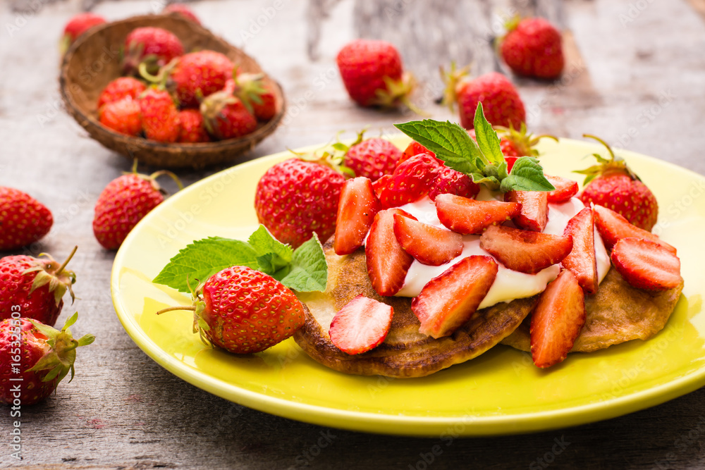 Pancakes with yogurt, sliced strawberries and mint leaves on a plate Pancakes with yogurt, sliced strawberries and mint leaves on a plate