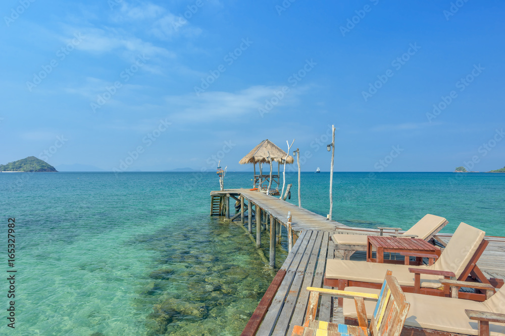 Wooden chair on pier in sea with beautiful tropical island, Thailand