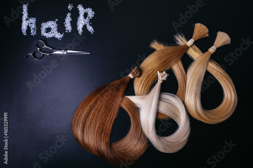 hair extensions of three colors on a dark background. copyspace. top view. photo