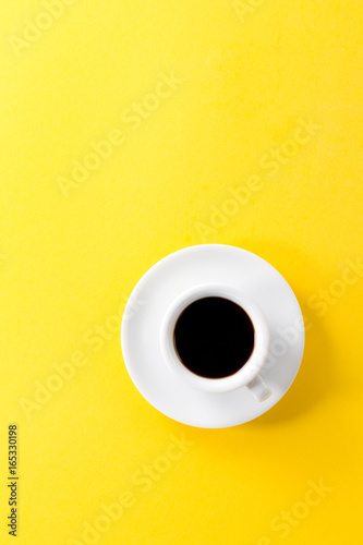 Coffee espresso in small white ceramic cup on yellow vibrant background