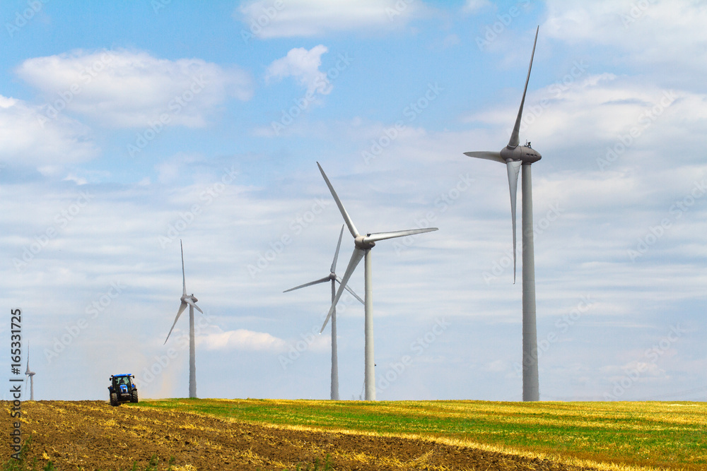 eolian wind turbine with plough tractor in the background eolian wind turbine with plough tractor in the background