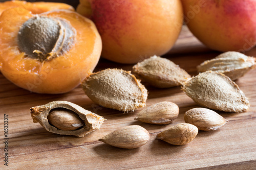 Apricot kernels and apricots on a wooden background