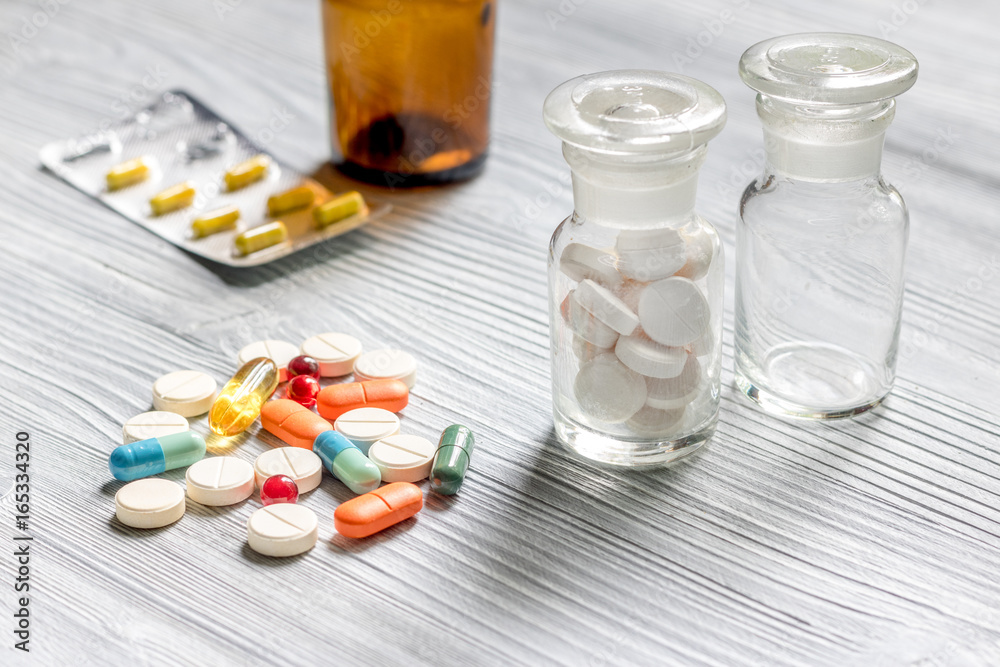 Pills and pill bottle on grey table background