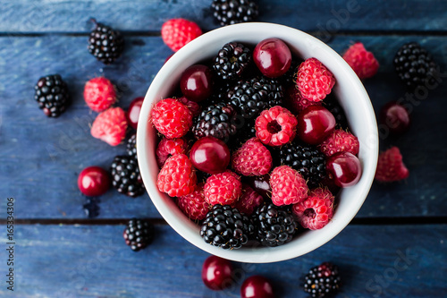 Foto Top view of white cup with Summer fresh berries on blue wooden table background