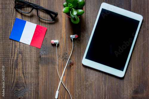 Self-development. Learning frensh online. Headphones and tablet PC on wooden background top view copyspace mockup