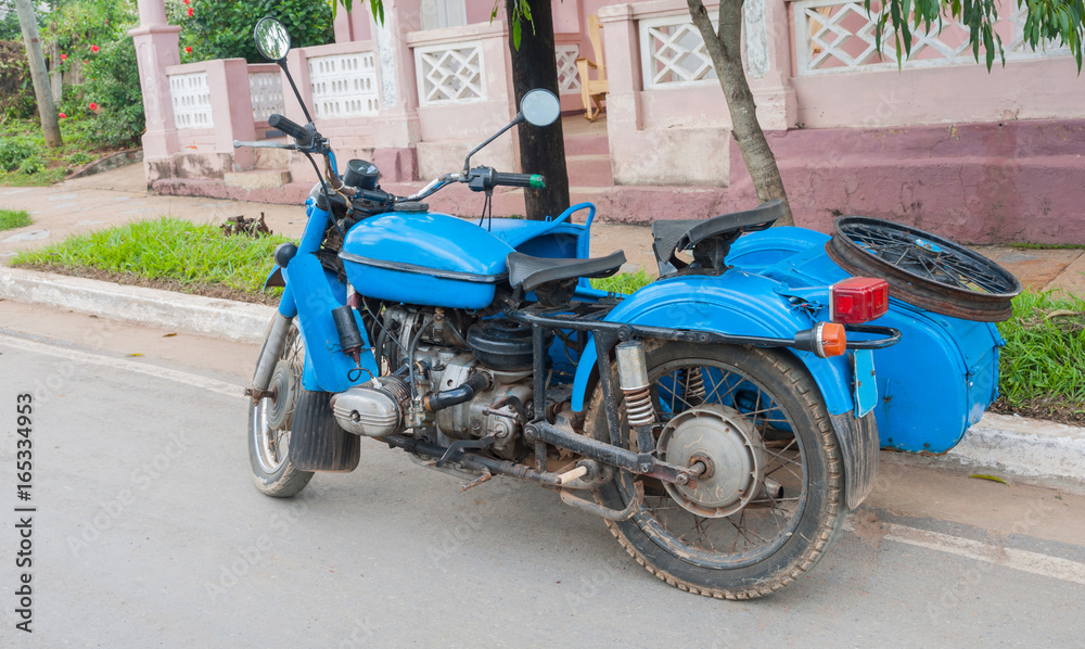 Old bright blue motorcycle with side car parked in Cuban street.