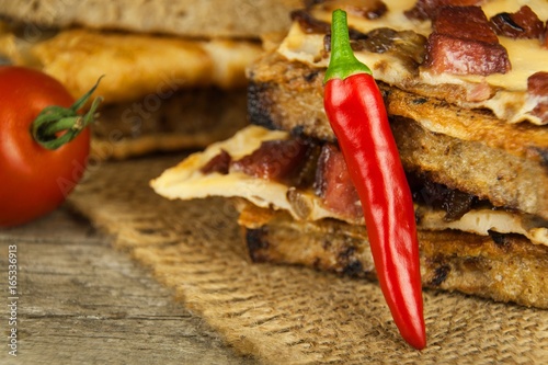 Roasted bread with egg omelet and chili pepper on a wooden table. Fastfood.