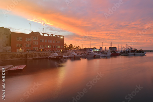 Fishing boats in Monipoli bay with sunset sky background, southern Italy