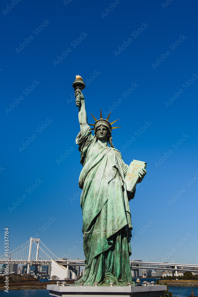 Fototapeta premium Statue of liberty against the sky. Statue of Liberty and Rainbow bridge, located at Odaiba Tokyo.