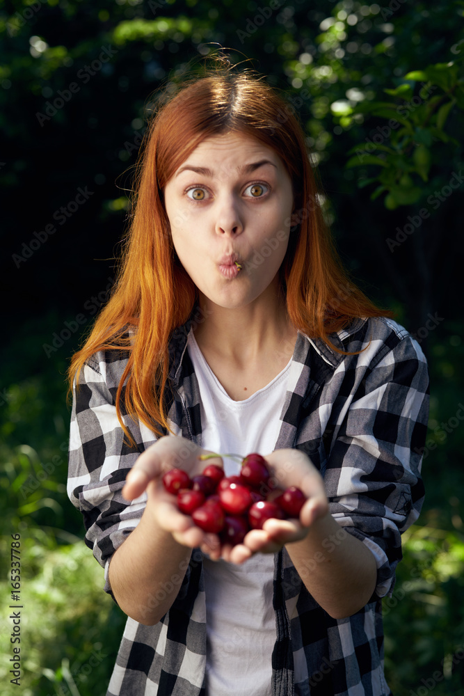 Beautiful young woman in the garden holds a cherry Beautiful young woman in the garden holds a cherry