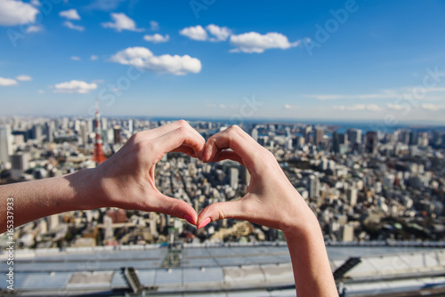 Female hands In form of heart against Tokyo Tower with skyline in Tokyo Japan. photo