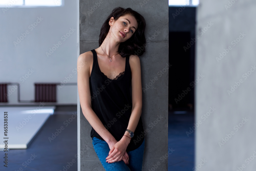 Smiling skinny female model standing at the wall wearing casual clothes Smiling skinny female model standing at the wall wearing casual clothes