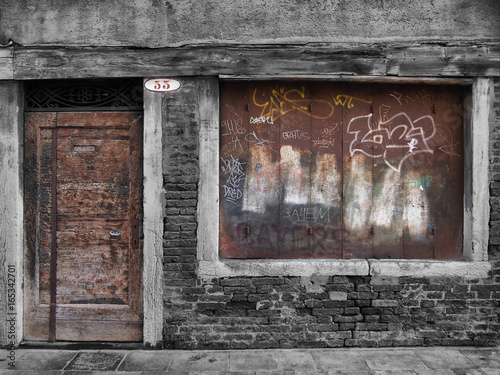 derelict decaying shop building with boarded up window and vandalism