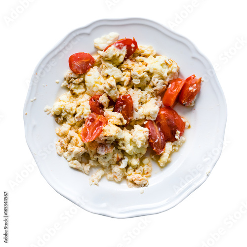 Fried eggs with slices of tomatoes in plate isolated on white