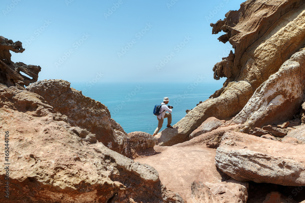 Tourist climbs the rock to make good shot of nature.