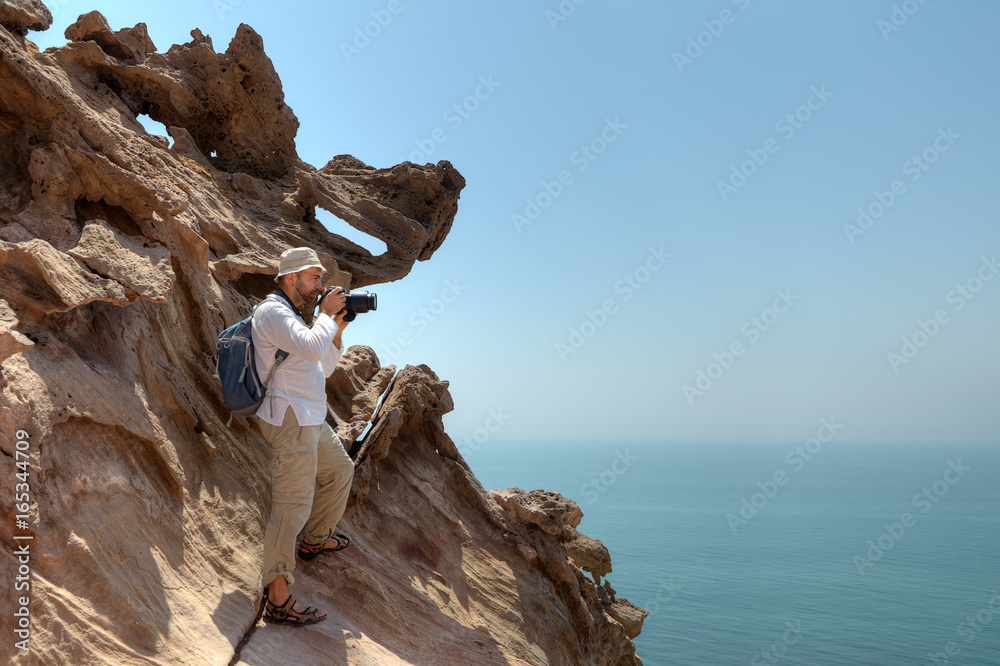 Traveler photographing nature, standing on edge of the cliff.