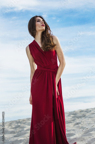 Beautiful girl in a red dress on the beach. Concept of femininity, harmony. photo