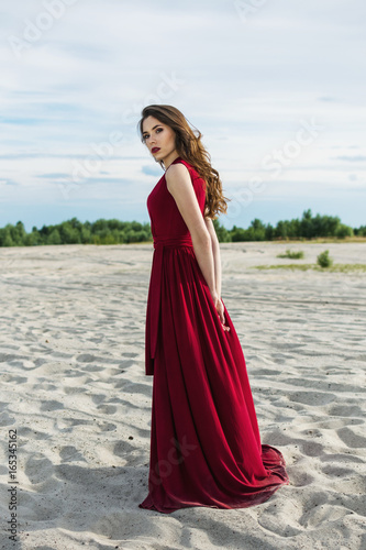 Beautiful girl in a red dress on the beach. Concept of femininity, harmony. photo