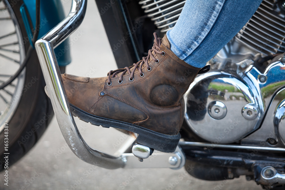 Obraz premium Side view at female foot with protective boot on the stands of chopper motorbike, close up