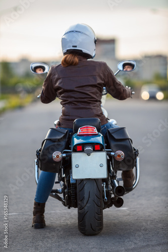 Rear view at the female motorcyclist sitting on the classic chopper motorbike photo