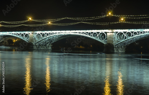 Iluminación nocturna del hermoso puente de Triana en la ciudad de Sevilla, España © Antonio ciero