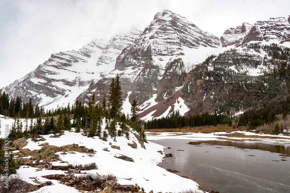 Obraz premium Clearing winter storm in the Colorado Rockies with snow and frozen lake