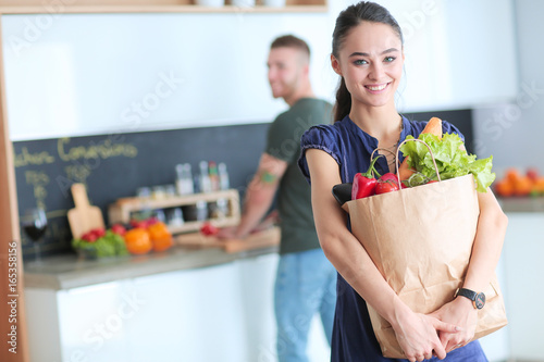 Young couple in the kitchen , woman with a bag of groceries shopping photo