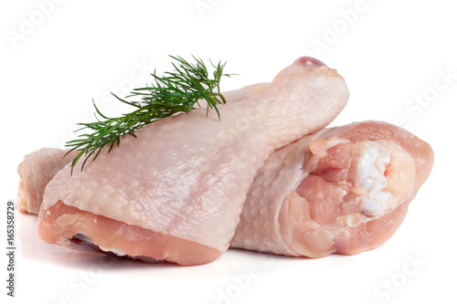 Two raw chicken drumsticks with a sprig of dill isolated on white background