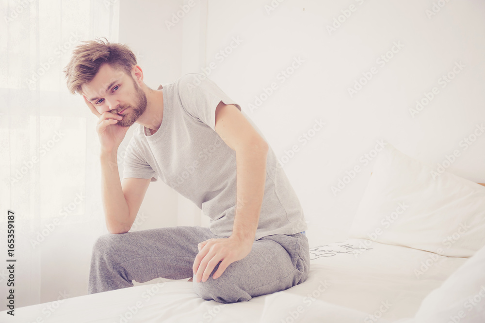 American man yawning. Man sitting a bed is serious and problem concept.