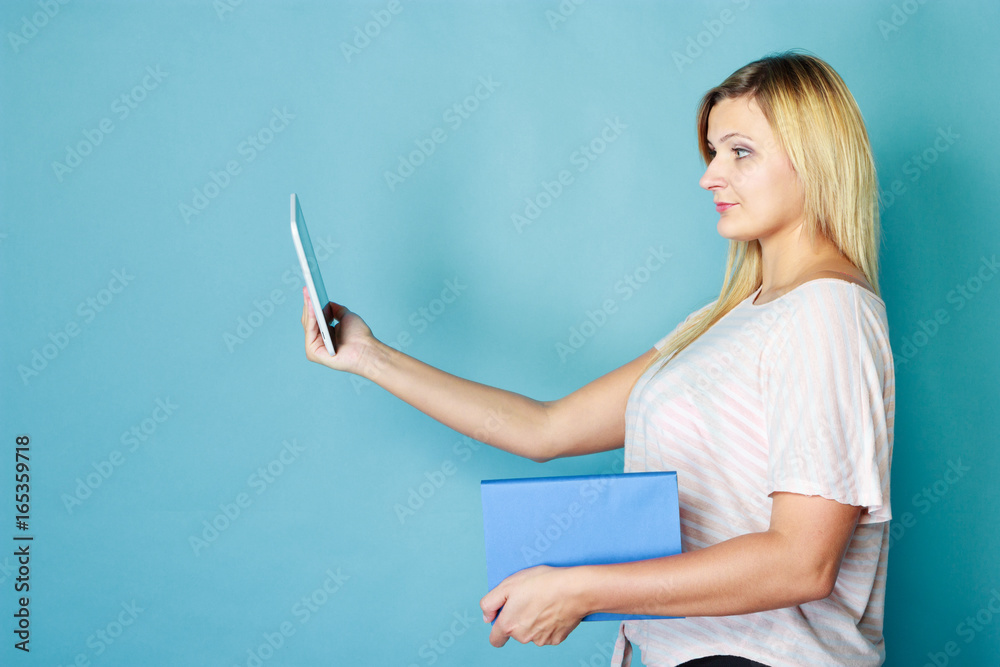 Blonde woman choosing between book and tablet Blonde woman choosing between book and tablet